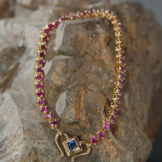 Gold necklace with pink gemstones and blue sapphire pendant, luxury jewelry on stone