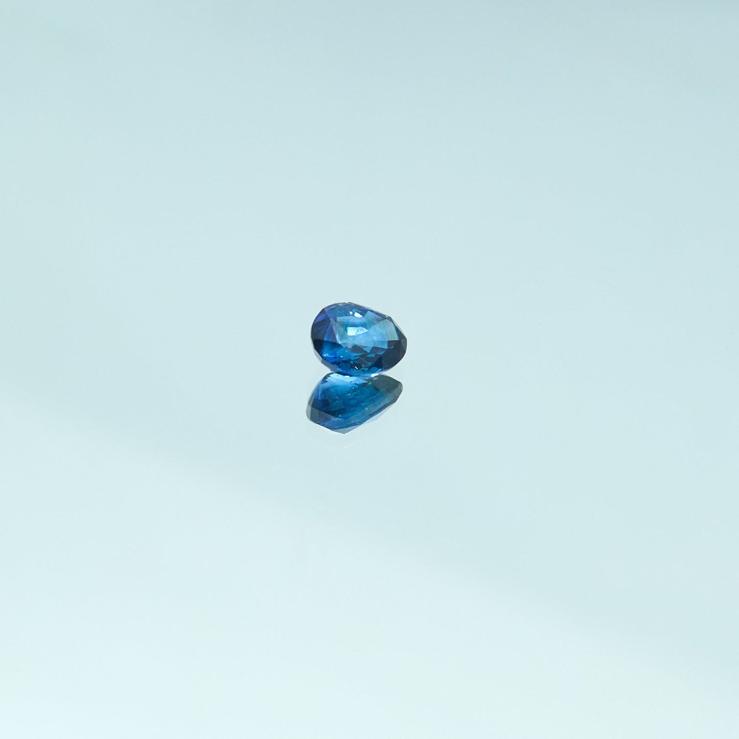 Faceted royal blue sapphire gemstone on reflective surface, luxury precious stone closeup