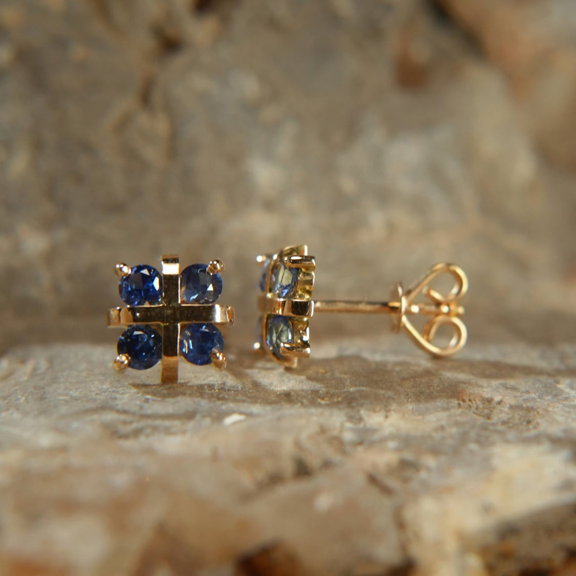 18K gold earrings with four blue sapphires from Eclat d'or on a stone background